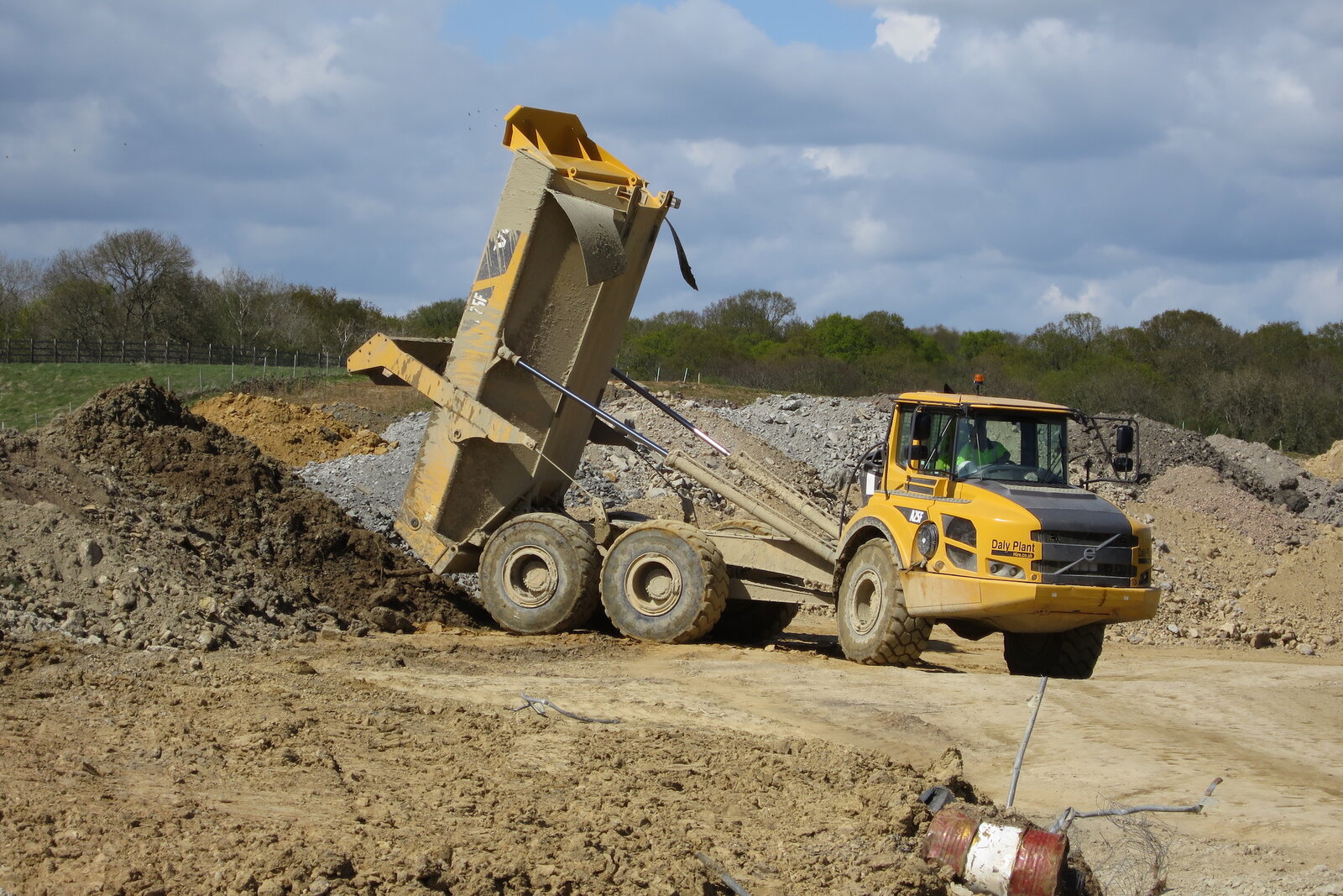 Articulated dump truck tipping a load of spoil on a muddy site